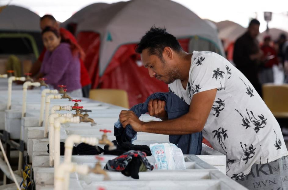 A man washes his clothes in a temporary sink in Mexico, near the United States border.