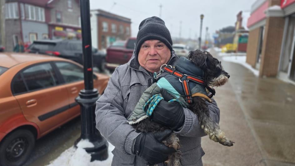 Do<em></em>nald Hunter holds his dog, Watson, while standing on the sidewalk.