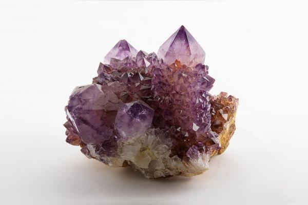 February birthstone: Four large, pointed purple crystals growing from a rock among similar smaller purple crystals.