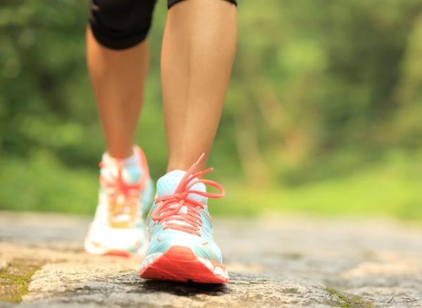 young fitness woman legs walking on forest trail