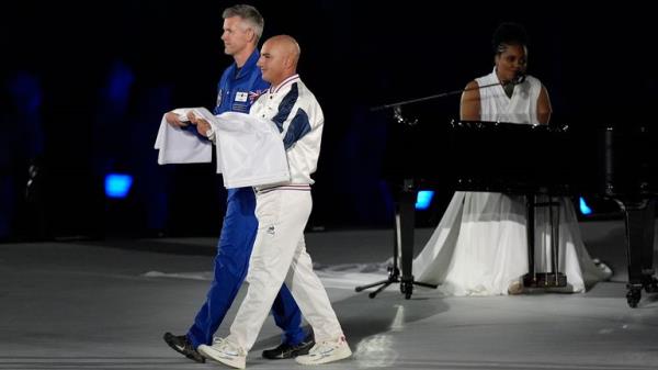 The Paralympic flag is brought on stage by John McFall (left) and Damien Seguin as the Paralympic Anthem is performed by Luan Pommier during the opening ceremony of the Paris 2024 Olympic Games at the Place de la Concorde. Picture date: Wednesday August 28, 2024. PA Photo. See PA story PARALYMPICS Ceremony. Photo credit should read: Andrew Matthews/PA Wire...RESTRICTIONS: Use subject to restrictions. Editorial use only, no commercial use without prior co<em></em>nsent from rights holder.