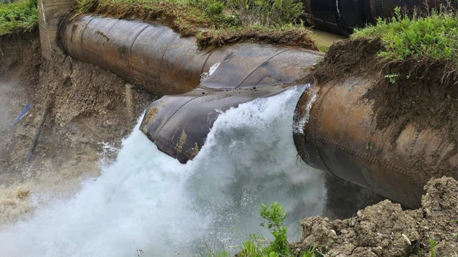 Water is bursting from a pipe and o<em></em>nto dirt.