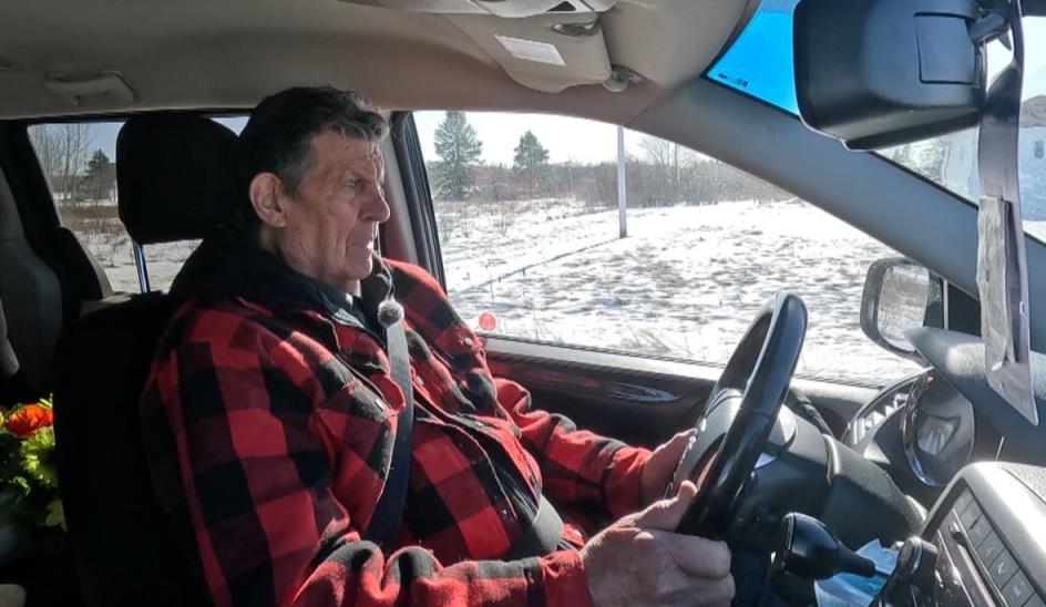 Man in plaid drives car. 