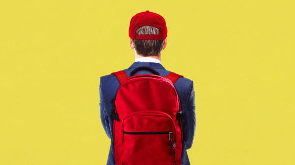 Young man in a suit wearing MAGA hat and red backpack