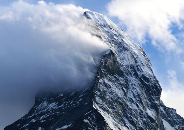 A cloud appears to stream off the side of a tall mountain peak.