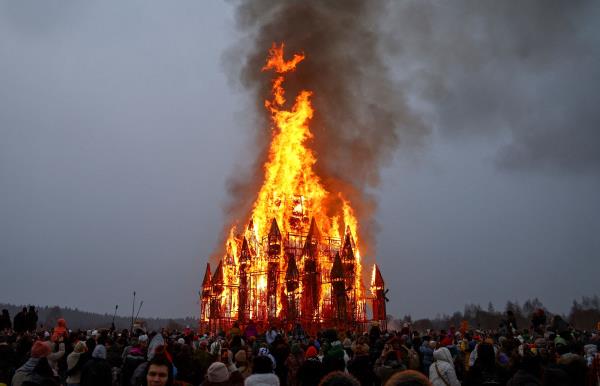 Revelers watch a giant wooden installation depicting a mill tower burn during the annual celebration of Maslenitsa at the Nikola-Lenivets art park southwest of Moscow, on March 1, 2025. The cherished Russian folk festival has its origins in an ancient Slavic holiday marking the end of winter and spring’s arrival.