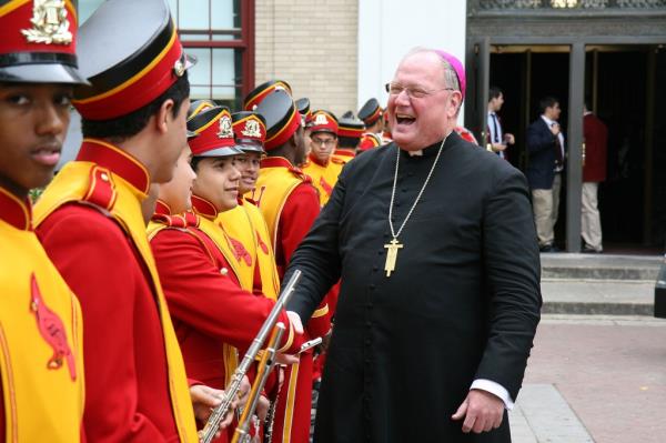 Archbishop Timothy M. Dolan shaking hands with people in uniform at the Regis Philbin Cardinal Hayes High School Auditorium Dedication in New York City.