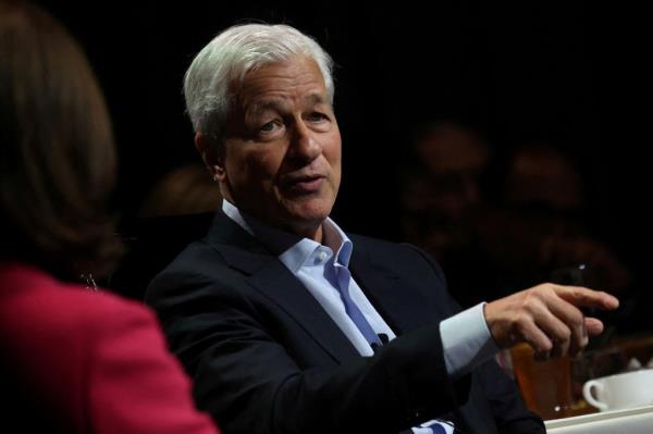 Jamie Dimon sitting in a chair looking relaxed and pointing.