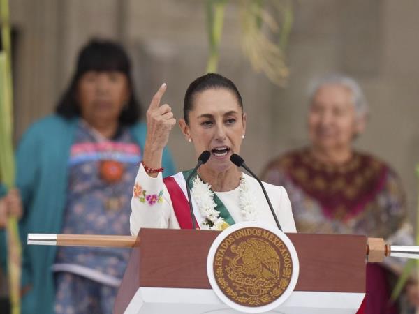 Claudia Sheinbaum at a microphone, gesturing with her right hand