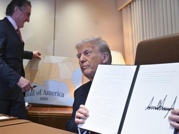 Do<em></em>nald Trump shows off a proclamation he signed as a staffer replaces a placard map behind him