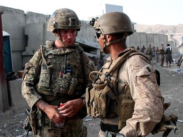 two soldiers in full combat gear conversing