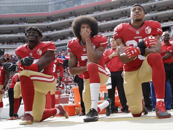 three nfl football players take a knee