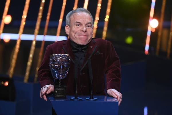 Warwick Davis accepts the Fellowship Award on stage during the 2025 BAFTA Film Awards.