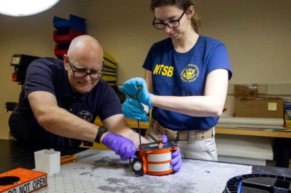 NTSB investigators examine a cockpit voice recorder and flight data recorder recovered following the collision, which killed 67 people.