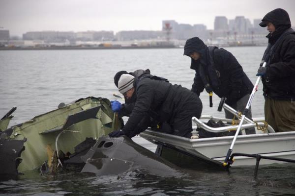 NTSB investigators and members of a salvage crew recover wreckage from the Army Black Hawk helicopter that collided with an American Airlines jet near Ro<em></em>nald Reagan Washington Natio<em></em>nal Airport last month.