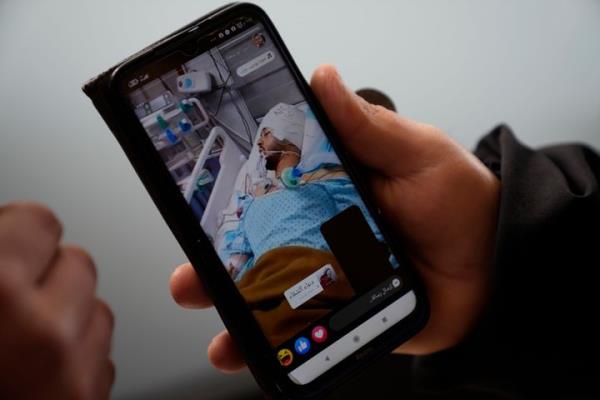 Mohammed Shula shows a picture of his hospitalized son, Yazan, while inside a relative's house wher<em></em>e he and his wife have taken refuge at the West Bank village of Kafr al-Labad, on Monday, Feb. 10, 2025.