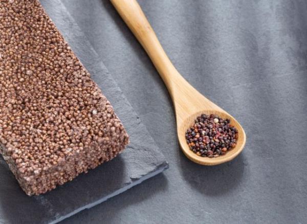 Quinoa crisp bar next to spoon full of quinoa